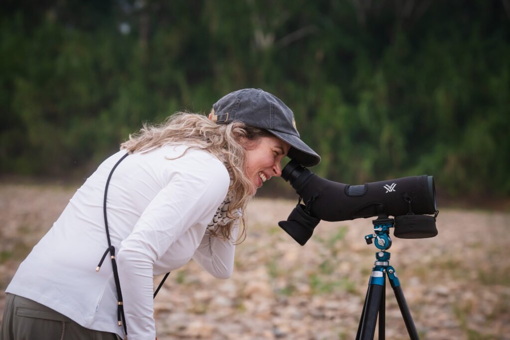 Traveler observing birds through a telescope during a birdwatching tour in Tambopata, in the Peruvian Amazon